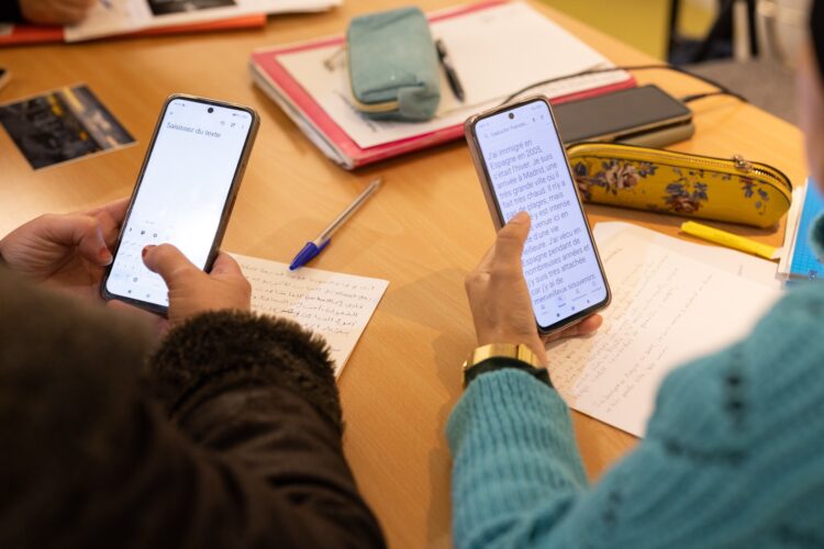Des gens utilisent leur telephone pour s'aider à traduire un texte en francais